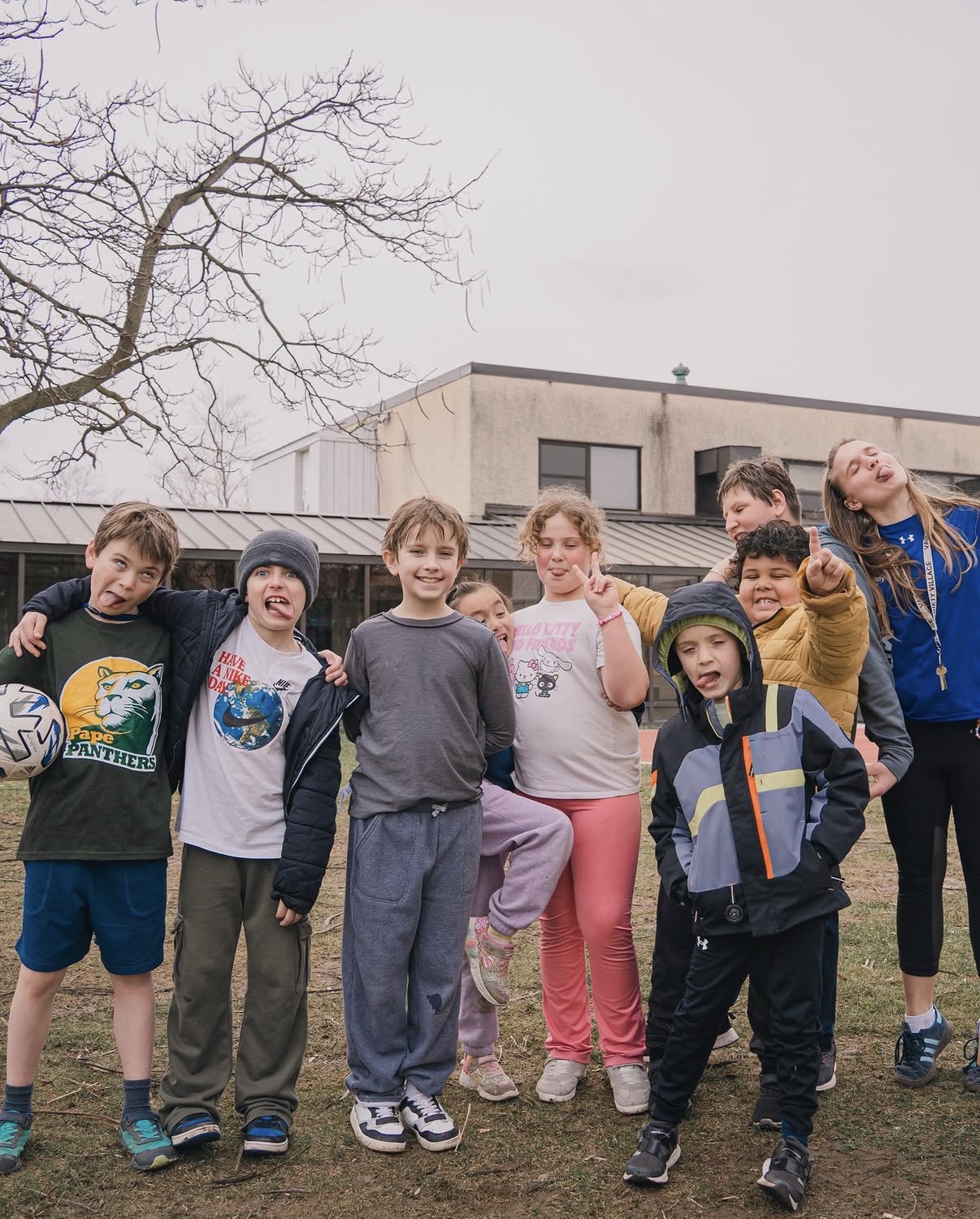 A group of children making silly faces outside