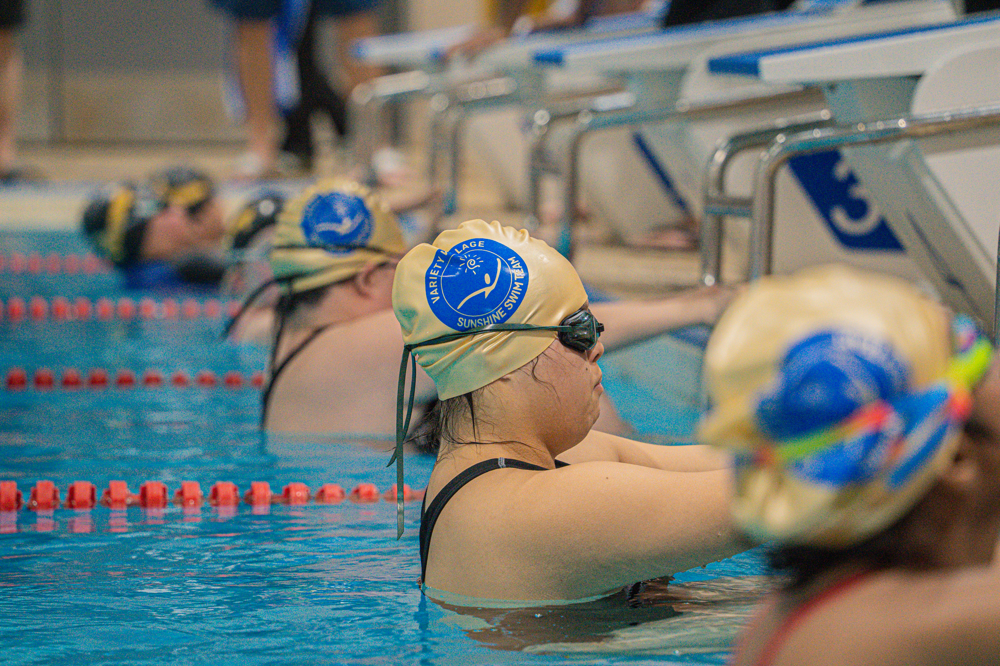 Swimmers hold onto the pool wall between races during a swim meet.