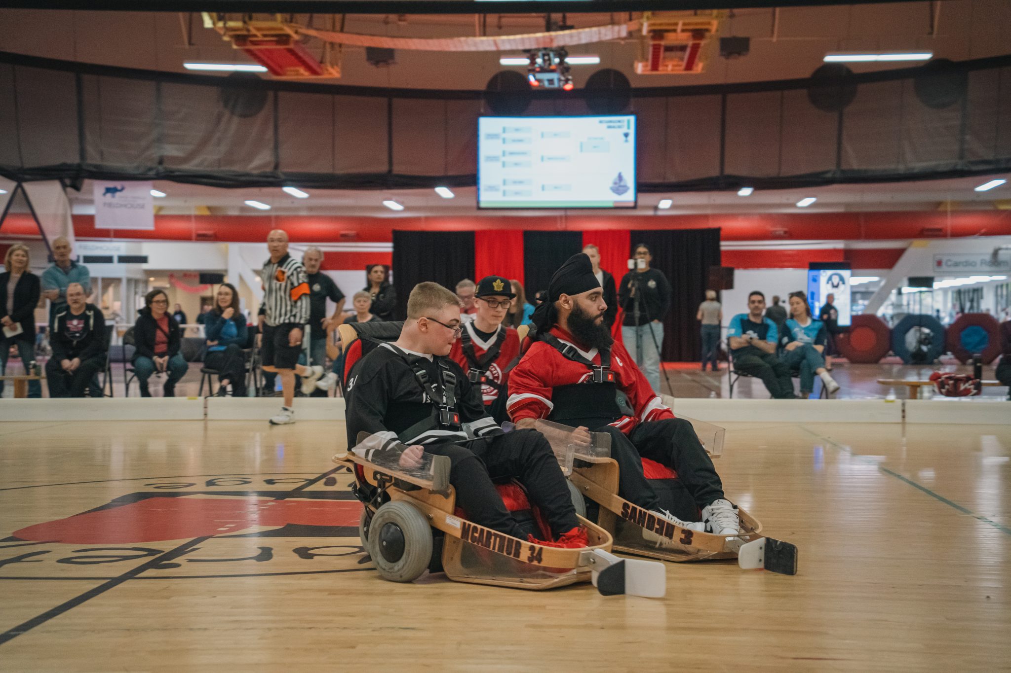 Two VOLT Hockey athletes compete during a game as spectators watch from the sidelines.