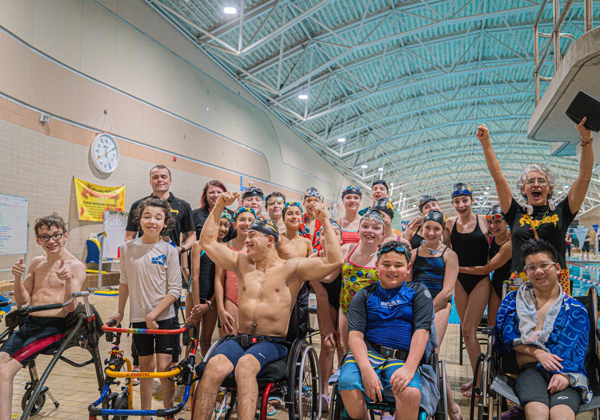 Variety Village swim team members and coaches gather for a celebratory group photo on the pool deck after a competition.