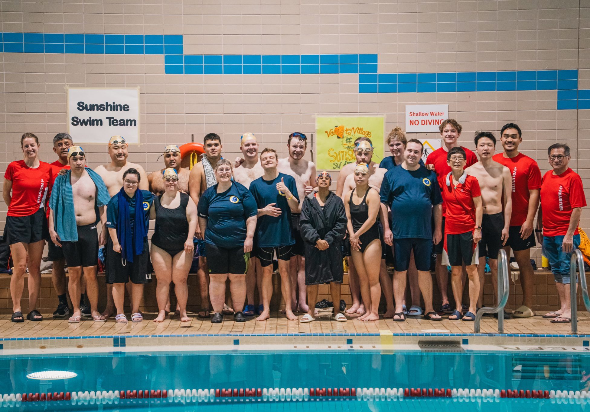 Sunshine Swim Team athletes, coaches, and volunteers stand together on the pool deck for a group photo.